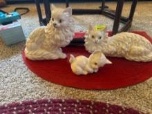 Three cat figurines very cute with a small red rug