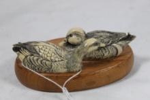Small ceramic pair of ducks on wood.