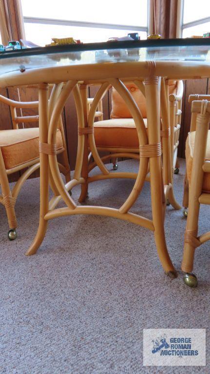 Rattan glass top table and four roll about chairs