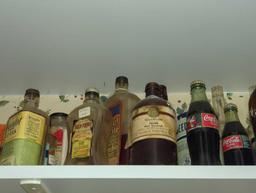 (KIT) PARTIAL SHELF LOT OF ASSORTED ITEMS TO INCLUDE, EARLY STYLE GLASS COCA COLA BOTTLE WITH SODA
