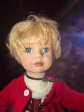 (GAR) Blonde Haired and Blue Eyed Porcelain Doll Wearing a White Shirt, Red Cardigan, and Black and
