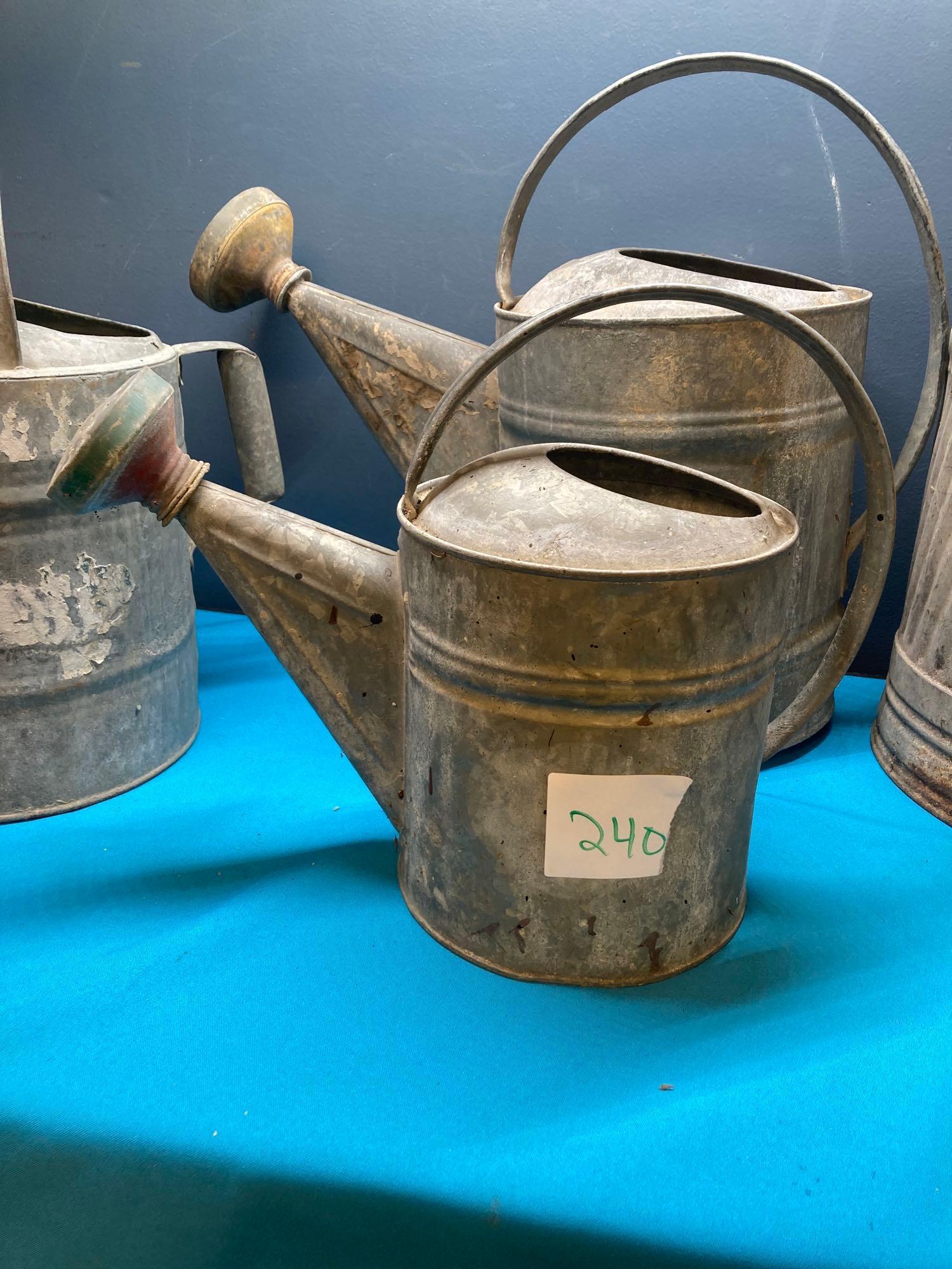 3 galvanized watering cans and a fuel can